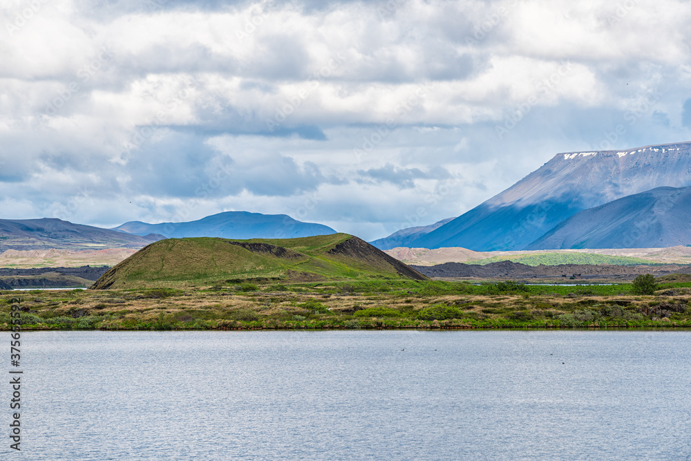 Landscape view of Iceland lake Myvatn mountains in Skutustadagigar during cloudy day and calm tranquil water and hill in summer