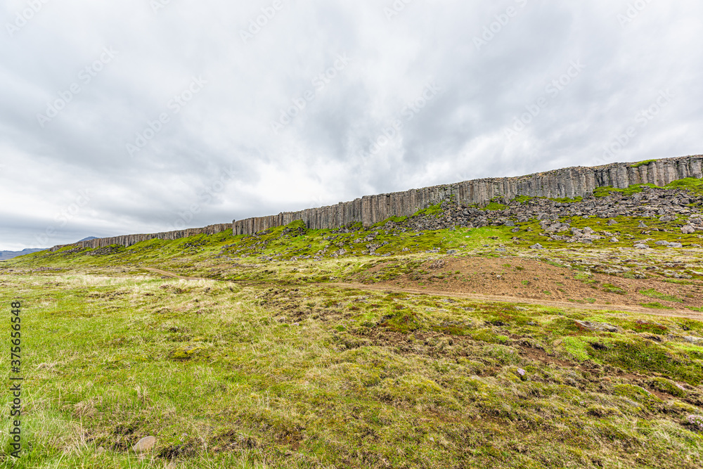 Gerduberg Basalt Columns wide angle view landscape in Snaefellsnes Iceland with green grass on summer day, stormy clouds and nobody