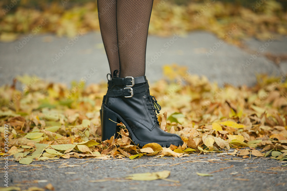 Black boots in a pile of yellow leaves Black boots in a pile of yellow leaves