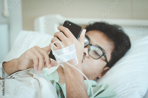 Obraz na płótnie A male patient use smart phone for social media and contact family member while in hospital. Recover from pandemic covid-19 or corona virus. Selective focus. w salonie