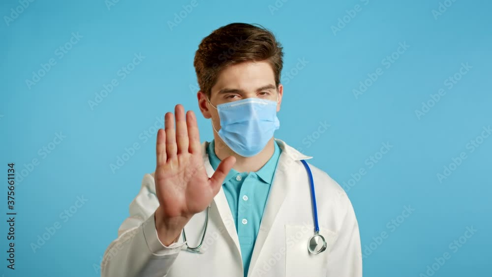 Portrait of serious doctor in professional medical white coat showing rejecting gesture by stop palm sign. Doc man isolated on blue background. Portrait of serious doctor in professional medical white coat showing rejecting gesture by stop palm sign. Doc man isolated on blue background.