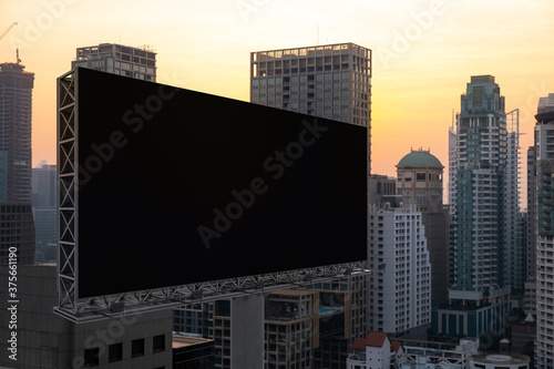 Blank black road billboard with Bangkok cityscape background at sunset. Street advertising poster  mock up  3D rendering. Side view. The concept of marketing communication to promote or sell idea.