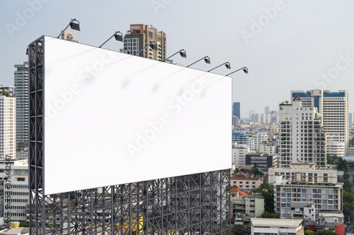 Blank white road billboard with Bangkok cityscape background at day time. Street advertising poster, mock up, 3D rendering. Side view. The concept of marketing communication to promote or sell idea.