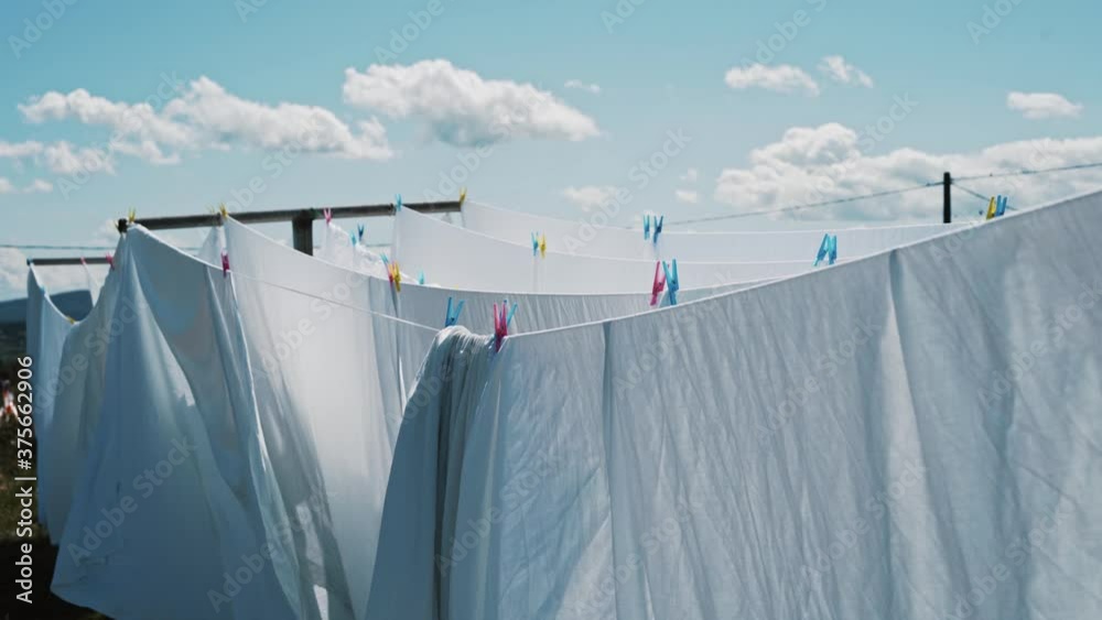 white bed sheets on a clothes line moving gently with the wind in a natural setting