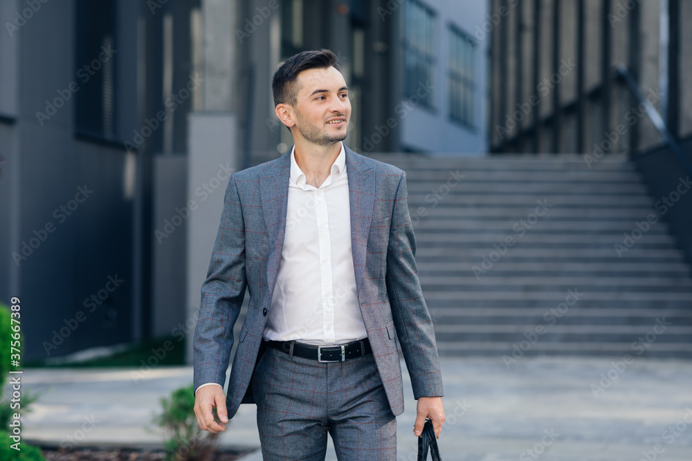 Modern businessman. Confident young man in suit looking away while standing outdoors with cityscape in the background. Handsome confident businessman portrait. Modern businessman. Confident young man in suit looking away while standing outdoors with cityscape in the background. Handsome confident businessman portrait.