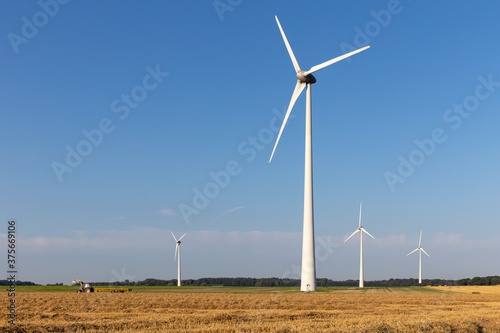 Ggroup of wind generators in a harvested field with a tractor