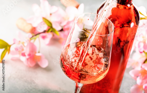 Εκτύπωση καμβά Rose wine pouring out of the bottle, gray bakcground, pink flowers