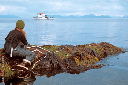 Young woman collecting biological samples on a rocky outcropping photo