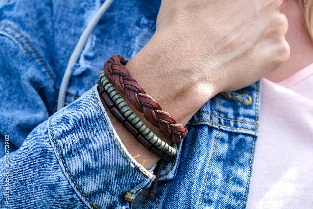 Leather ethnic braided bracelets on woman wrist close up, hippie woman  wearing jeans, denim jacket and boho accessories on a hand, bohemian style  Stock Photo | Adobe Stock
