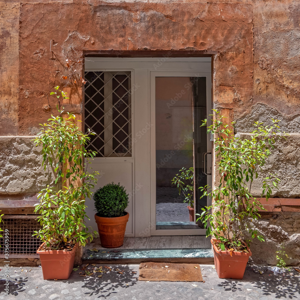 vintage house facade with white door and flowerpots, Trastevere old neighborhood, Rome Italy