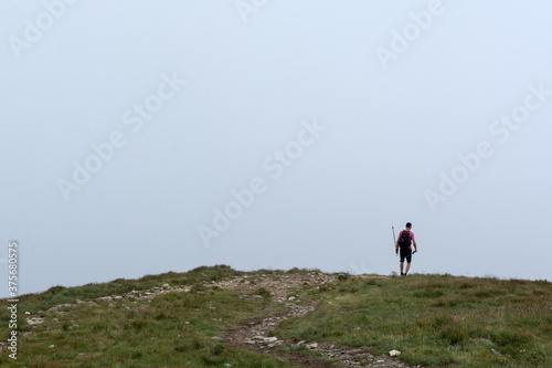 man with trekking sticks walking in the mountains