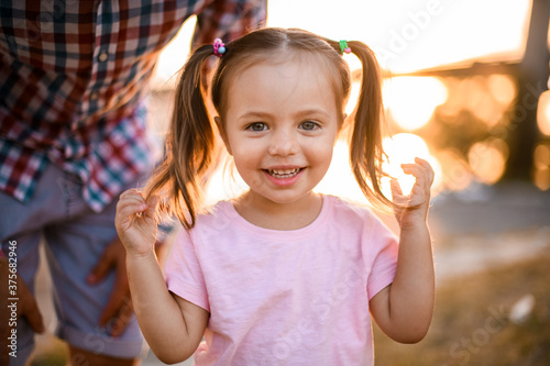 little cheerful blonde girl with two ponytails look at camera