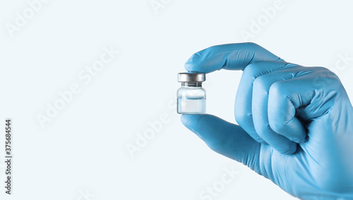 Schilderij op canvas A vial of vaccine for injection in the doctor's hand on a light blue background