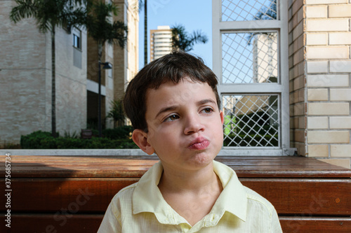 7 year old Brazilian child, on a sunny afternoon, chewing the chocolate with his mouth closed and looking to the side. photo