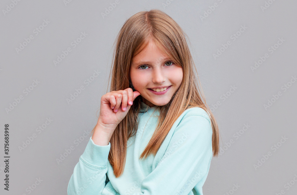 Portrait of young beautiful cute cheerful girl smiling looking at camera over gray background. Portrait of young beautiful cute cheerful girl smiling looking at camera over gray background.