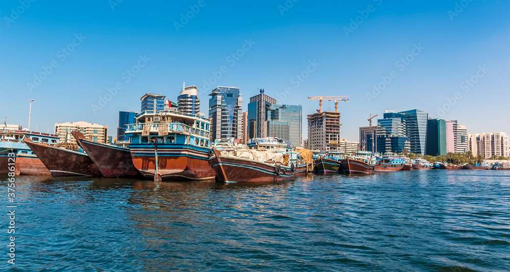 Fototapeta premium Dhow boats and modern skyscrapers on the Dubai Creek in the UAE in springtime