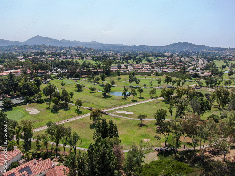 Aerial view of golf in middle class neighborhood surrounded with residential house, and mountain on the background in San Diego, South California, USA.
