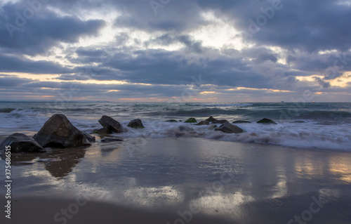 Foaming wave breaking at sunrise with rocky shoreline