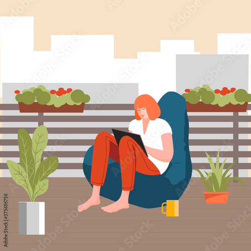 Concept red-haired girl reading on a terrace in the city.