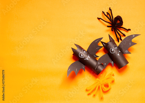 Halloween holiday concept. Two halloween toy bat, spiders on the orange background. DIY For kids. Handcraft creative idea from toilet tube, recycle concept. Home decor project party