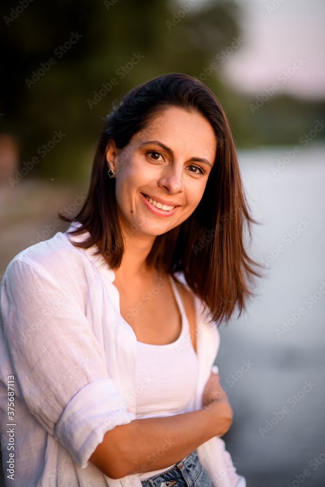 Attractive young smiling dark haired woman in white clothes