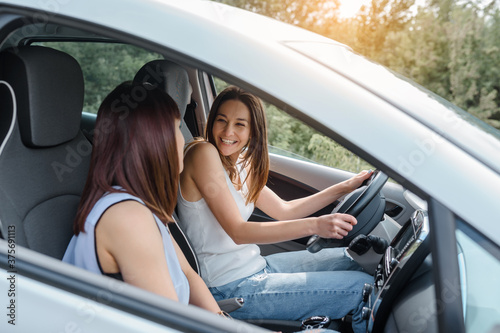 Two happy young women friends are driving a car and enjoy the company. T © Med Photo Studio