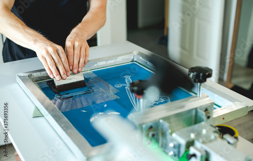 Fotografia Cropped view of man wiping plastisol ink from stencil on screen printing machine
