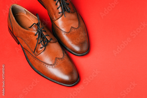 Brown leather shoes close-up on a red background with a copy of the space. Stylish and fashionable shoes made of genuine leather. Men fashion