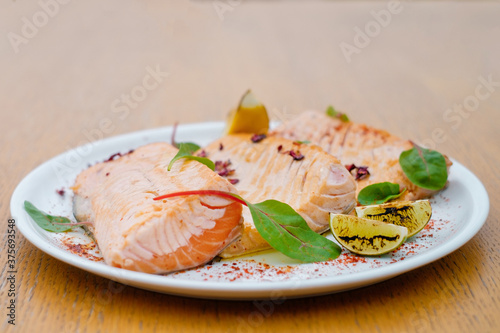 Grilled fish garnished with lemon and basil close up. Decorated catering banquet menu with different food snacks and appetizers with sandwich.