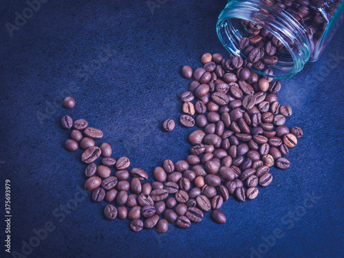 scattered coffee beans from a glass jar on a black background. coffee mood. coffee background