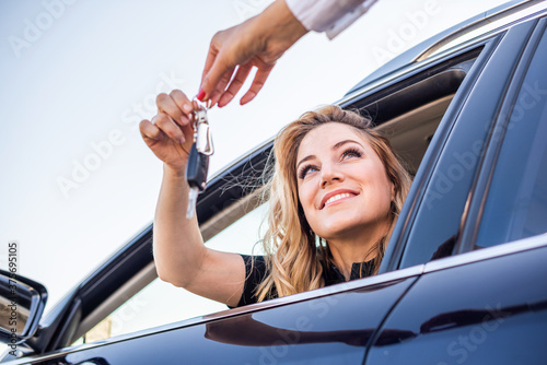 Obraz na płótnie Beautiful woman gets the key from the car while sitting behind the wheel. w salonie