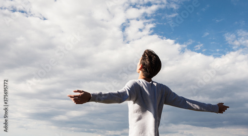 Happy and free young man feeling good with open arms towards the blue sky. Inspiration and freedom. © PKpix