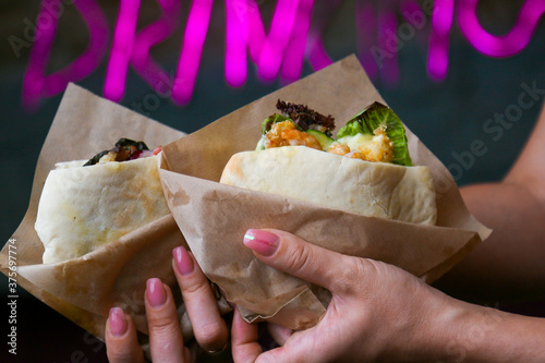 Close-up on hands of an Israeli teenage girl in white shirt holding pita with falafel and salad, with an Israeli flag toothpick topper decoration for Israel's Independence Day celabrations photo