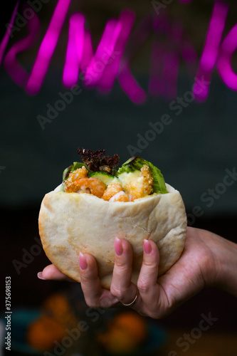 Close-up on hands of an Israeli teenage girl in white shirt holding pita with falafel and salad, with an Israeli flag toothpick topper decoration for Israel's Independence Day celabrations photo