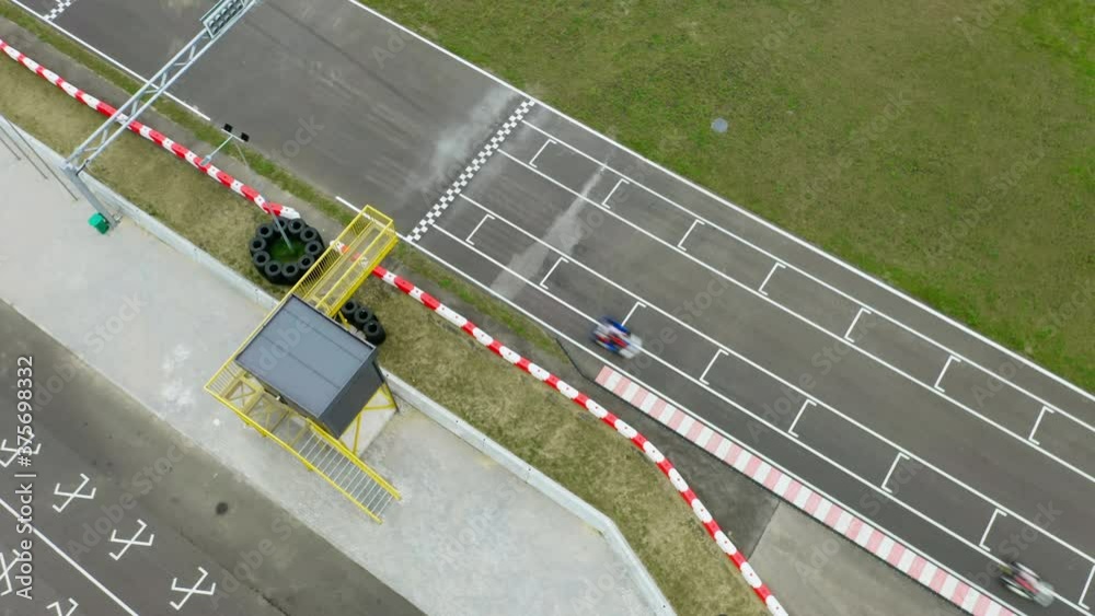 Aerial top down view drone flies over racing cars driving on race track. Kart racing open wheel motorsport. Racing go-karts cross finish line in competition