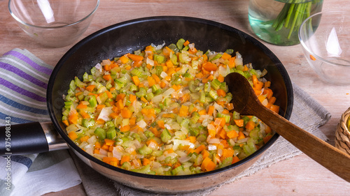 The preparation of fried vegetable filling of onions carrots and celery - ready Mirepoix or Soffritto in a frying pan.