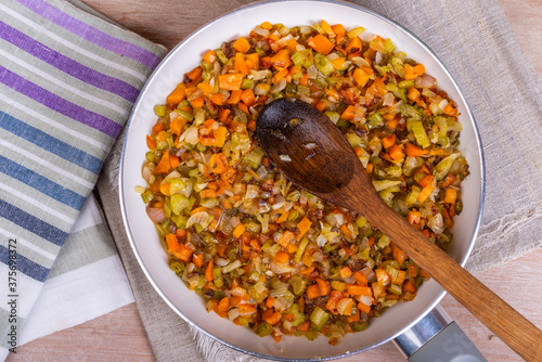 The preparation of fried vegetable filling of onions carrots and celery - ready Mirepoix or Soffritto in a pan, top view. photo