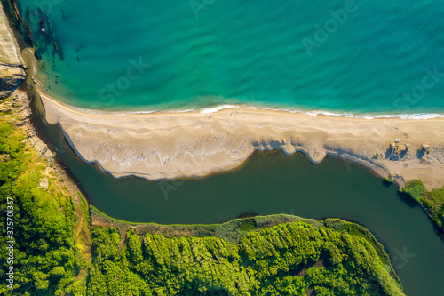 Beautiful sandy beach surrounded by sea waves on one side and on the other by the waters of a river that flows into the sea, the mouth of Veleka River at the Black sea coast, Bulgaria photo