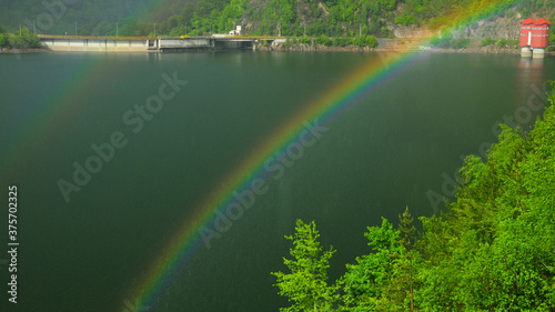 Double rainbow in a rainy day over Bradisor lake in summer season. Lotru Mountains  Carpathia  Romania.