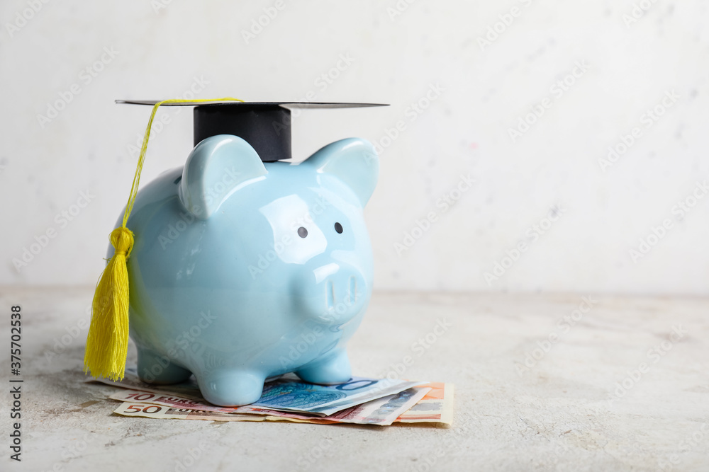 Piggy bank with graduation hat and money on table. Tuition fees concept - obrazy, fototapety, plakaty 