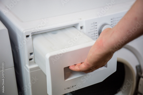 clothes dryer water tank, man maintains the machine regularly, empties the water tank, cleans the filters, etc.