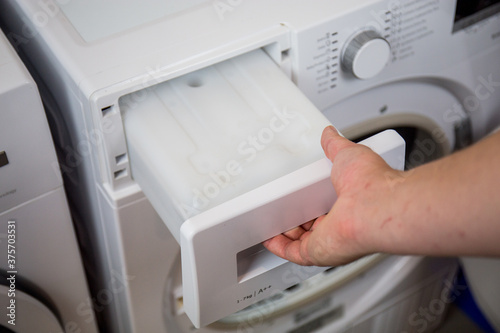 clothes dryer water tank, man maintains the machine regularly, empties the water tank, cleans the filters, etc.