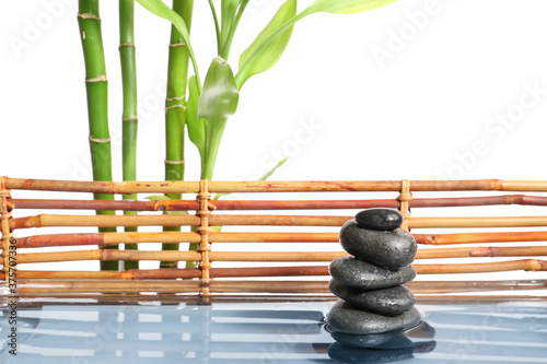 Stack of spa stones and bamboo in water on white background