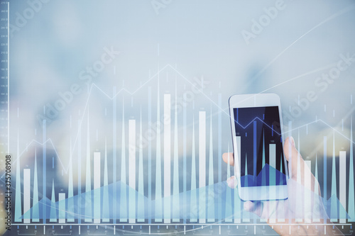 Double exposure of forex chart sketch hologram and woman holding and using a mobile device. Stock market concept. © peshkova