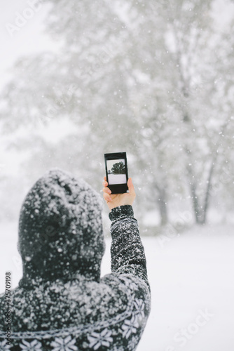 Woman taking a photo of snowy trees photo