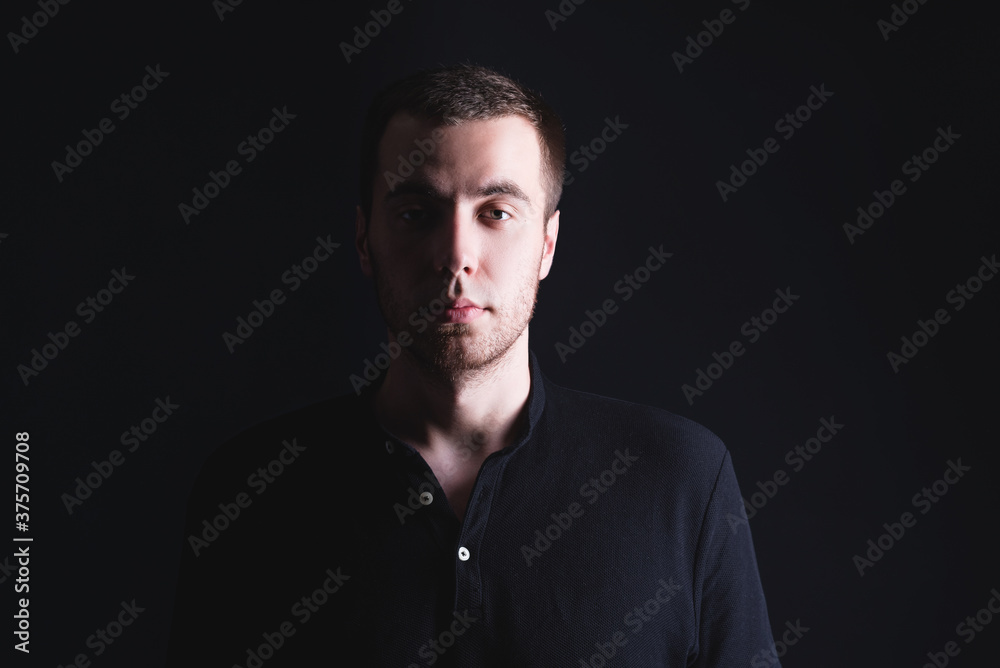 Portrait of an emotional handsome young man, on a black background in the studio, who stands in a brooding pose. Expression of emotions and feelings Portrait of an emotional handsome young man, on a black background in the studio, who stands in a brooding pose. Expression of emotions and feelings