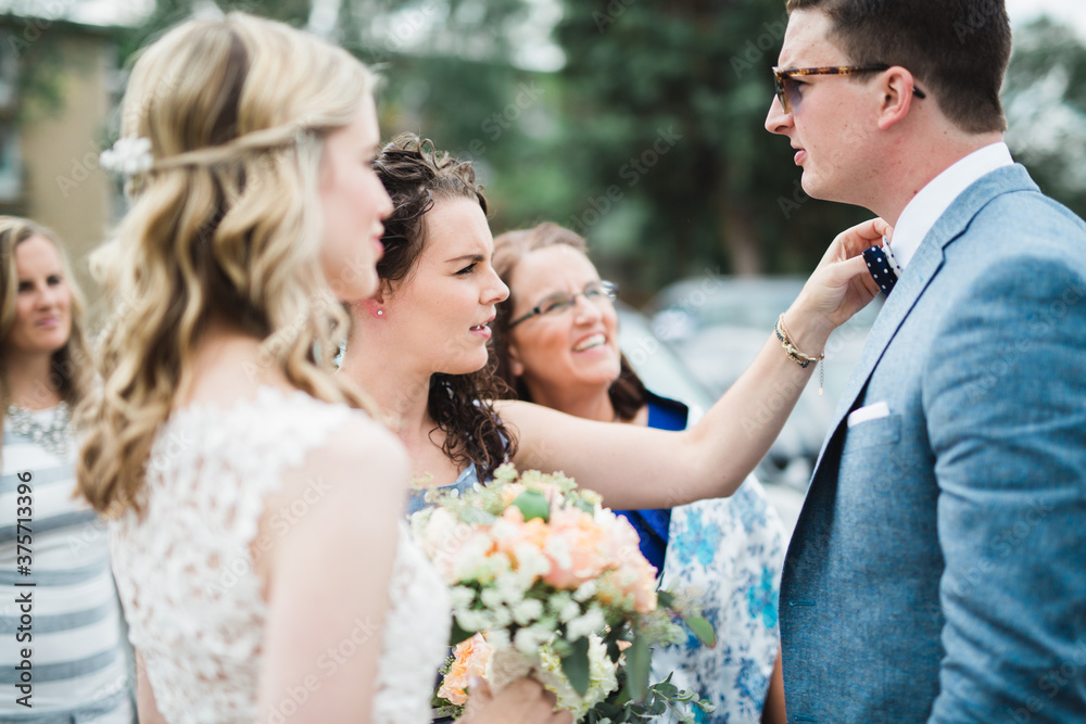 Bridesmaid fixing groom's bow tie Bridesmaid fixing groom's bow tie