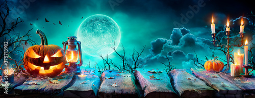 Fotografia Jack O’ Lantern On Table In Spooky Night - Halloween With Full Moon