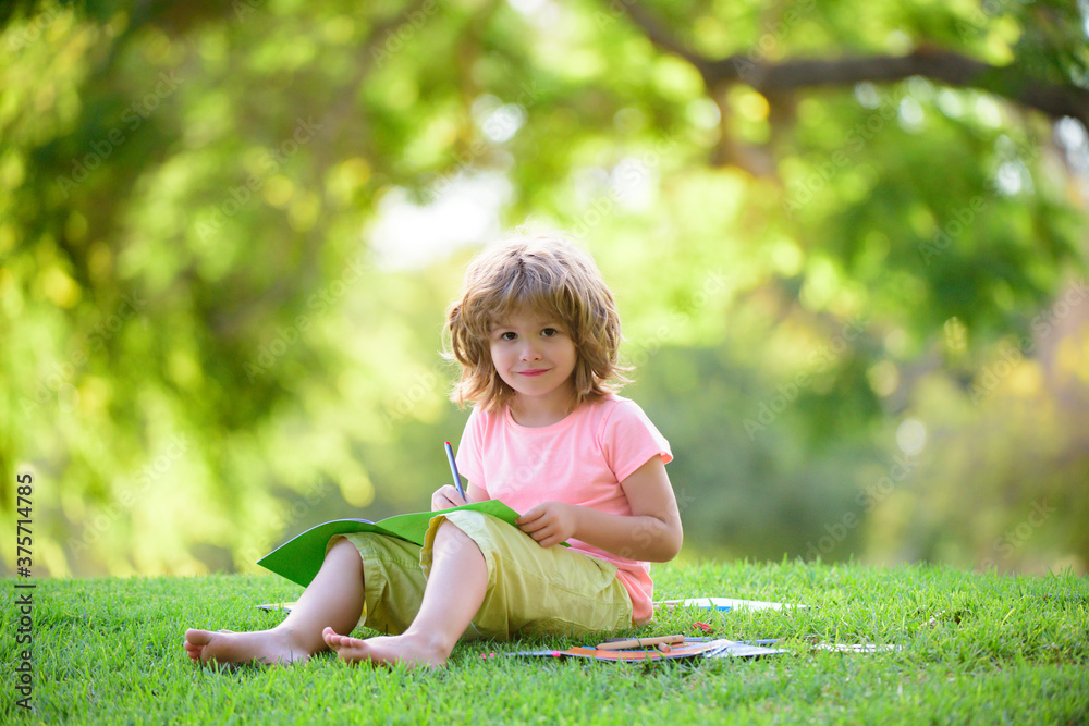 Cute little pupil studying in park and smiling Outdoor kids education. Cute little pupil studying in park and smiling Outdoor kids education.