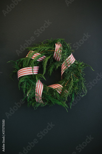 Handmade festive Christmas wreath with red ribbon on dark background photo